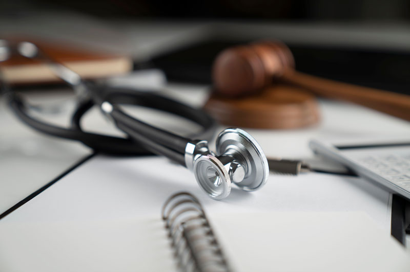 Gavel, notebook and stethoscope on the white table